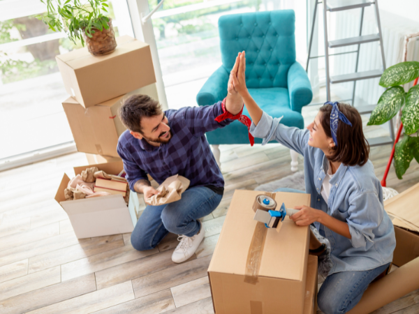Couple high five as they pack boxes for move to cape town