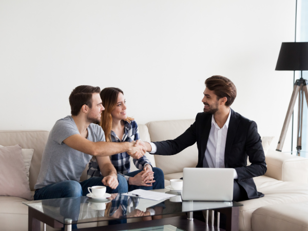 Landlord shaking hands with happy young couple in new home