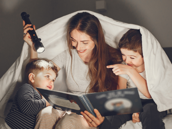 Mother reading to her two young sons by flashlight