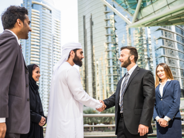 Multiethic business people shaking hands in front of Dubai buildings