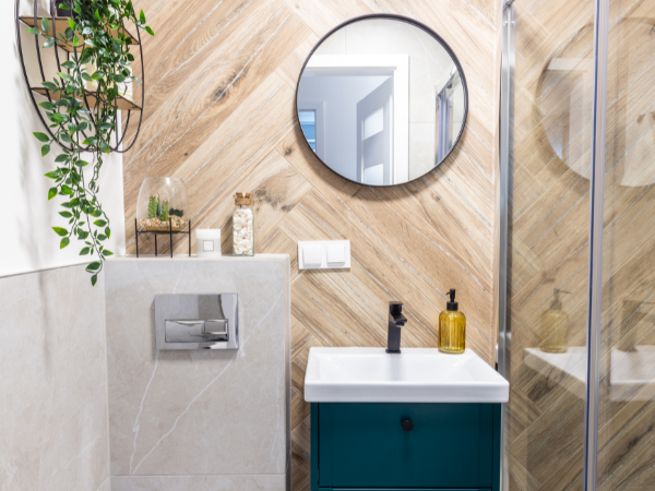 Small bathroom design with wooden panelling, round mirror, and indoor plant