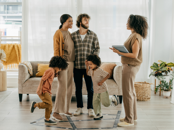 Young family with children speaking to real estate agent in home lounge