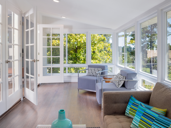 bright white sunroom with chairs and colourful cushions