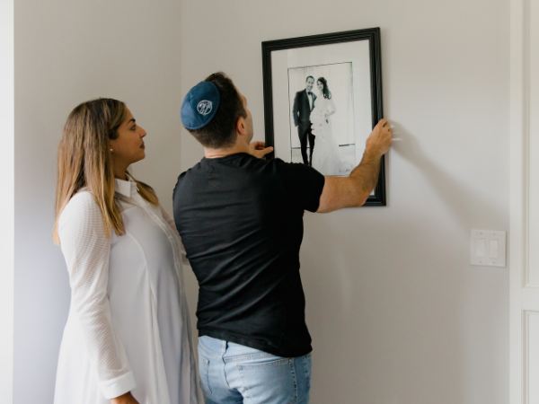 couple hanging a wedding photo on white wall