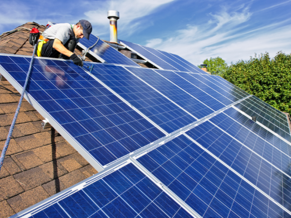handyman installing solar panels on residential roof