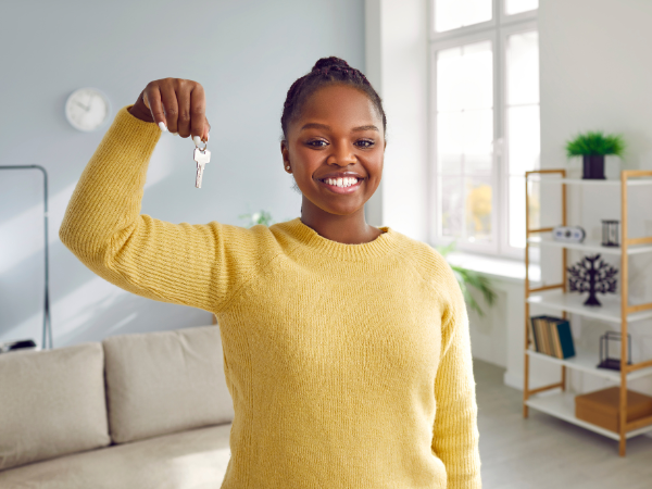 happy african american woman holding keys and standing in new house