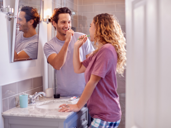happy couple brushing their teeth in en-suite bathroom