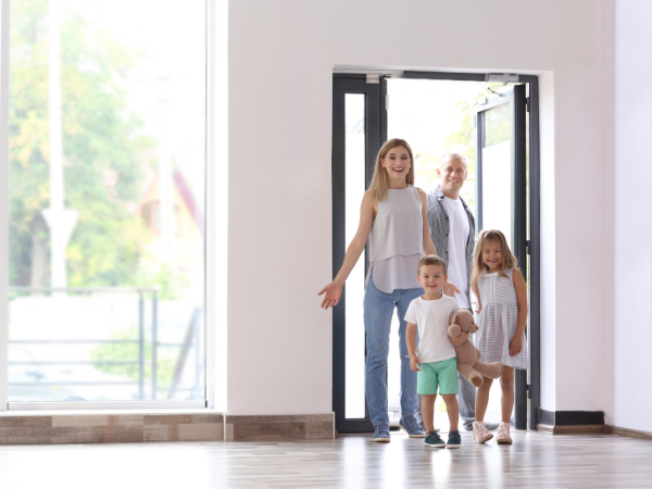 happy family entering light-filled hallway of their new home 
