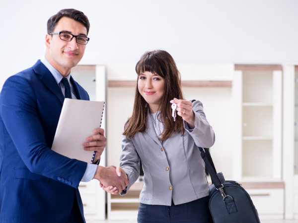 happy landlord holding keys and shaking hands with real estate agent