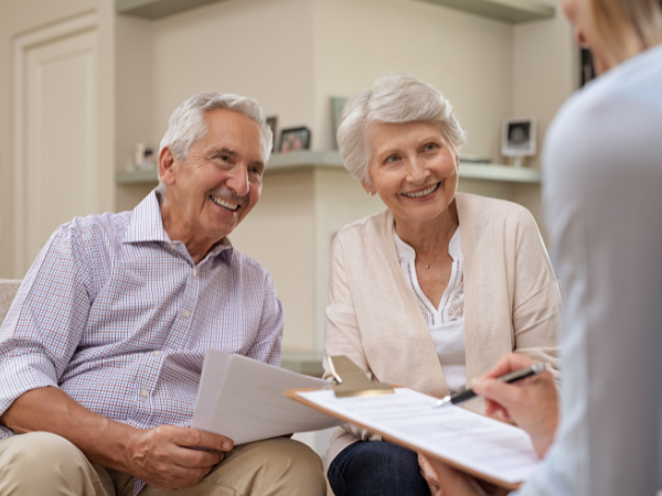 happy older couple discussing property price with real estate agent