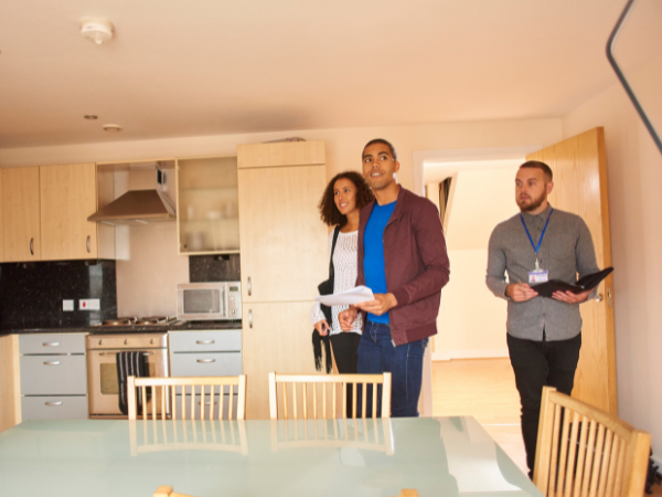 home viewing with real estate agent showing young couple the kitchen