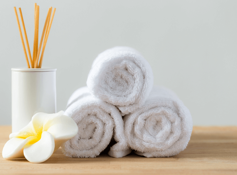 white rolled up towels next to scented stick diffuser
