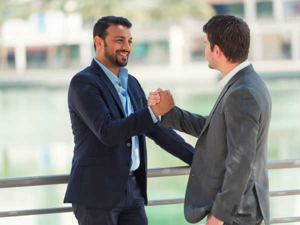 two happy middle eastern men shaking hands