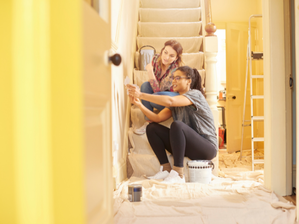 two women painting the hallway with bright yellow