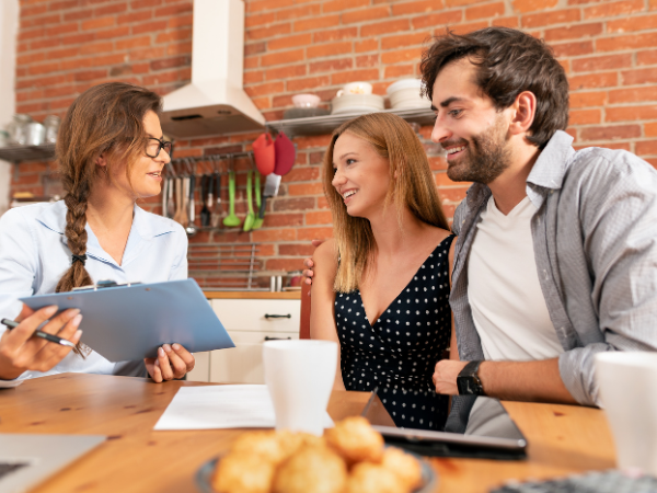 female real estate discussing property with young buyers in rustic kitchen