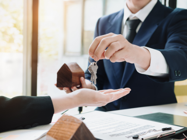 real estate agent handing keys to individual after signing rental property investment agreement