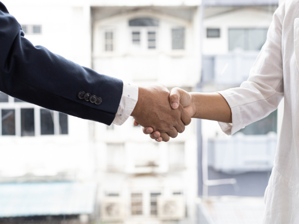 Real estate agent shaking hands with client in front of an apartment building