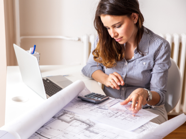 woman sitting at desk viewing blueprint of her house
