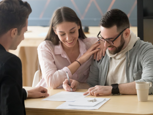 young couple signing a contract with their real estate agent