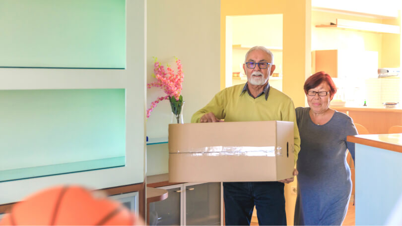 Happy retired couple smiling moving and packing up boxes